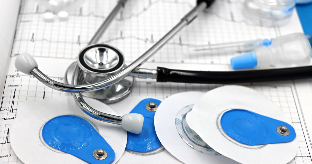 Eletrodos e estetoscópio sobre um traçado de eletrocardiograma
