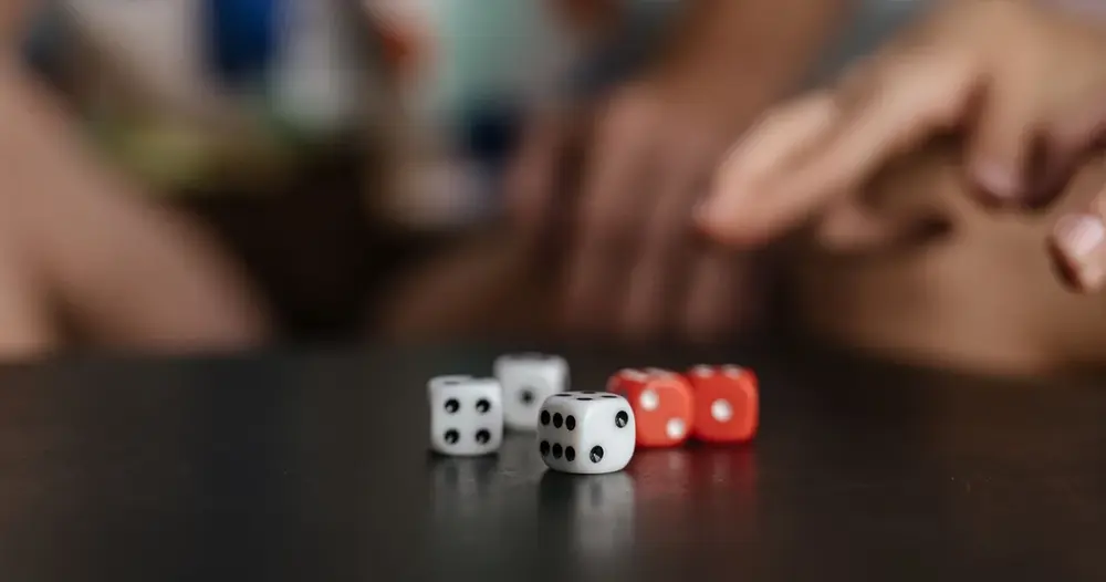 Dados brancos e vermelhos sobre uma mesa escura, imagem para sites de dado online de 1 a 6