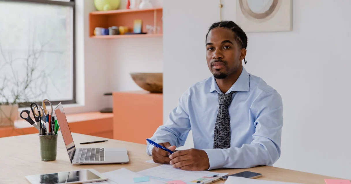 Pequeno empresário sentado à mesa com notebook no escritório